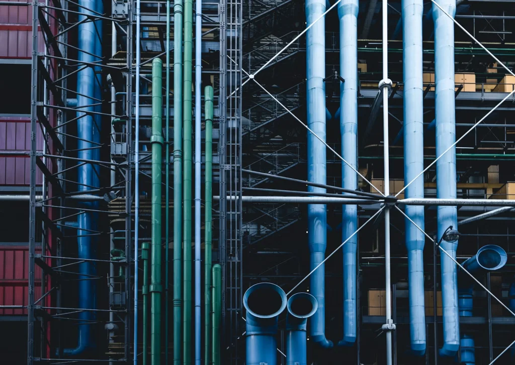 Modern building exterior with colorful pipes and metal framework. (@heytowner for Unsplash)