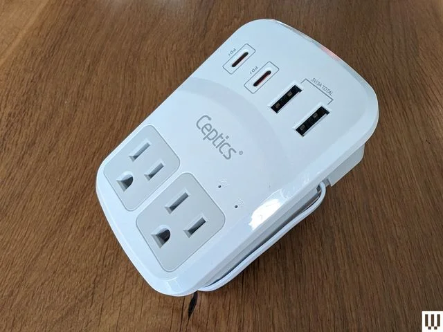 Small white electronic travel adapter with various outlets
