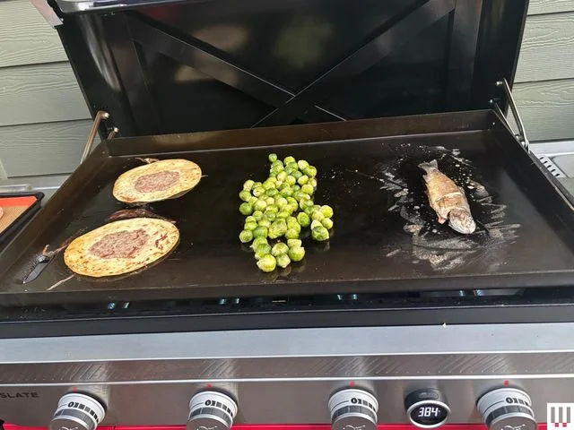 Closeup of a black griddle with food cooking on top