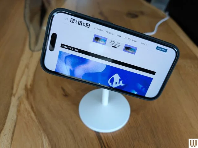 Anker MagGo Wireless Charging Stand a narrow white pole with circular top to which a mobile phone is attached in...
