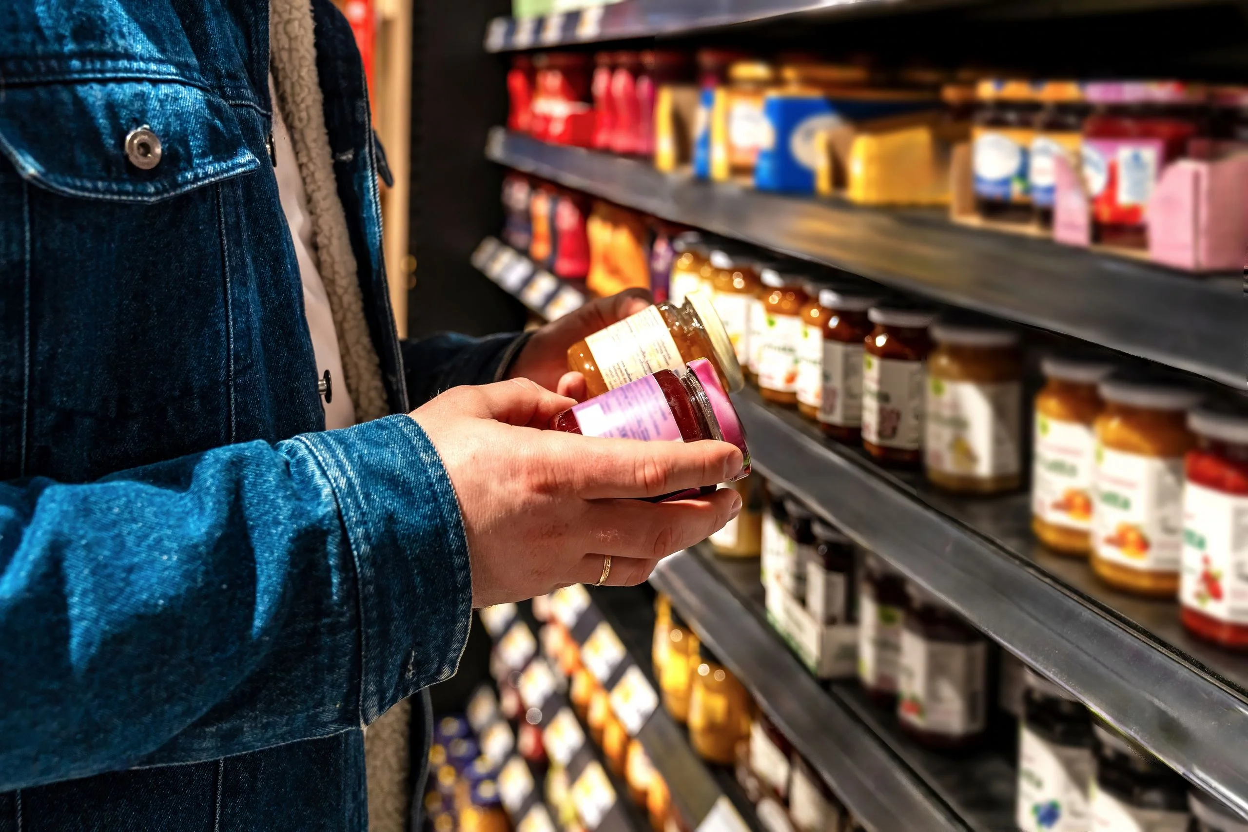 man reading jar label on shelf checking ingredients and nutrition