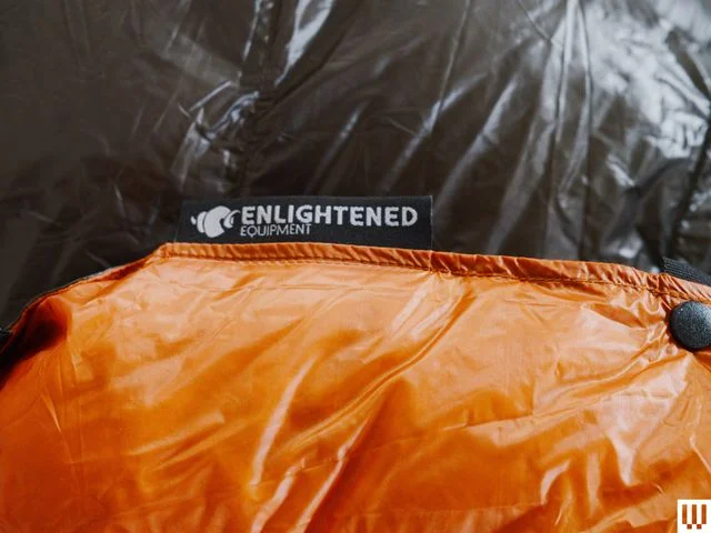 Closeup of puffy quilt with orange exterior and grey interior