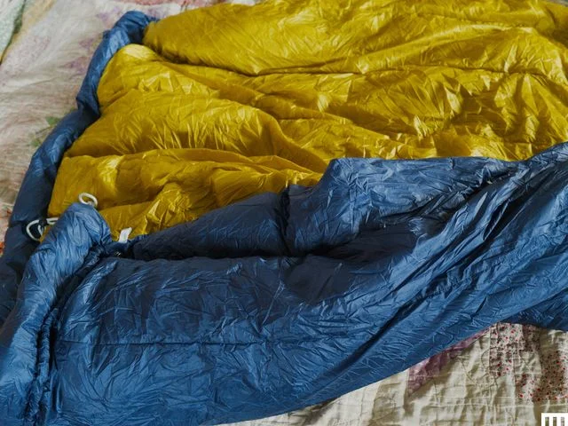 Closeup of puffy navy blue quilt, unzipped to show yellow interior