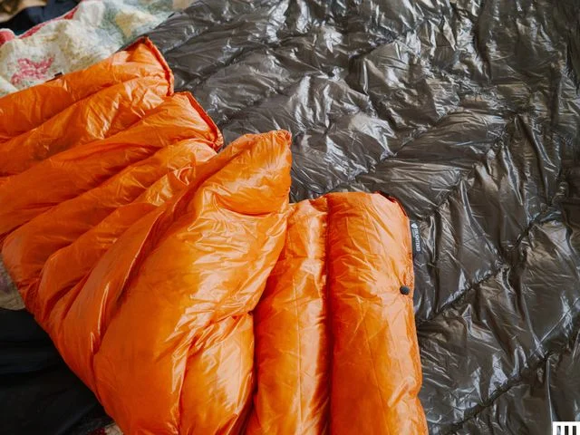 Closeup of puffy quilt, semi folded with orange exterior and grey interior