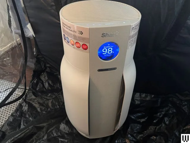 White cylindrical air purifier sits in black tent