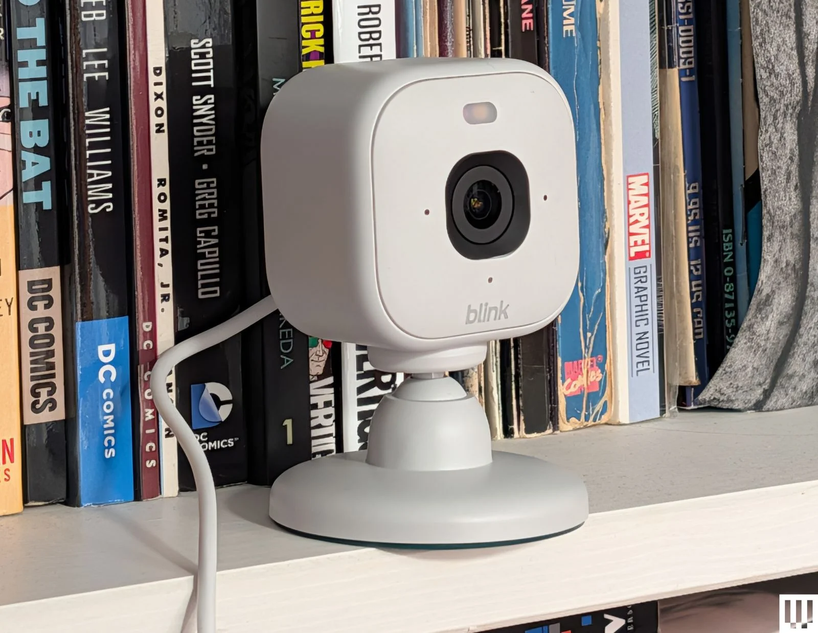 Small white squareshaped camera on a bookshelf