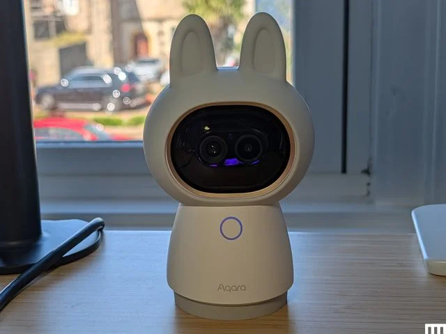 Home camera in the shape of a white cute figure with pointy ears, the screen for the face, and a cone shaped body